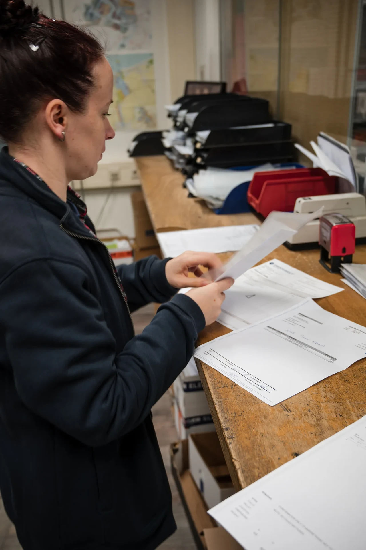 An Imatech employee reviews shipping documents at a warehouse desk, working with a practical, hands-on approach to ensure accurate and efficient order processing.